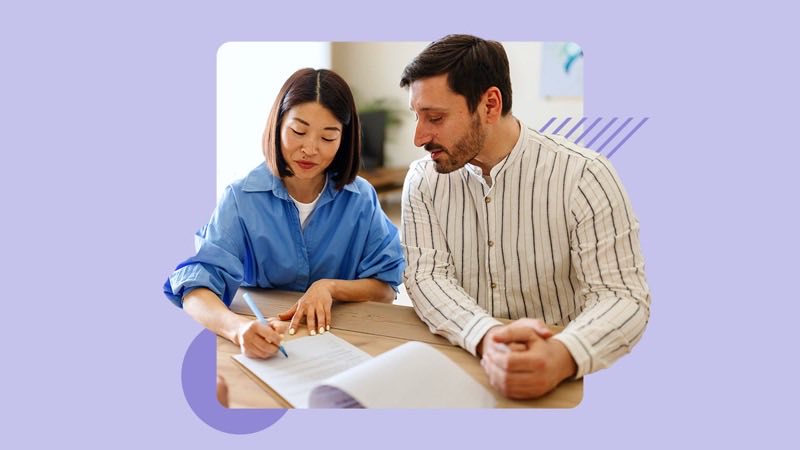 A couple going through mortgage paperwork together at a table, one of them taking notes