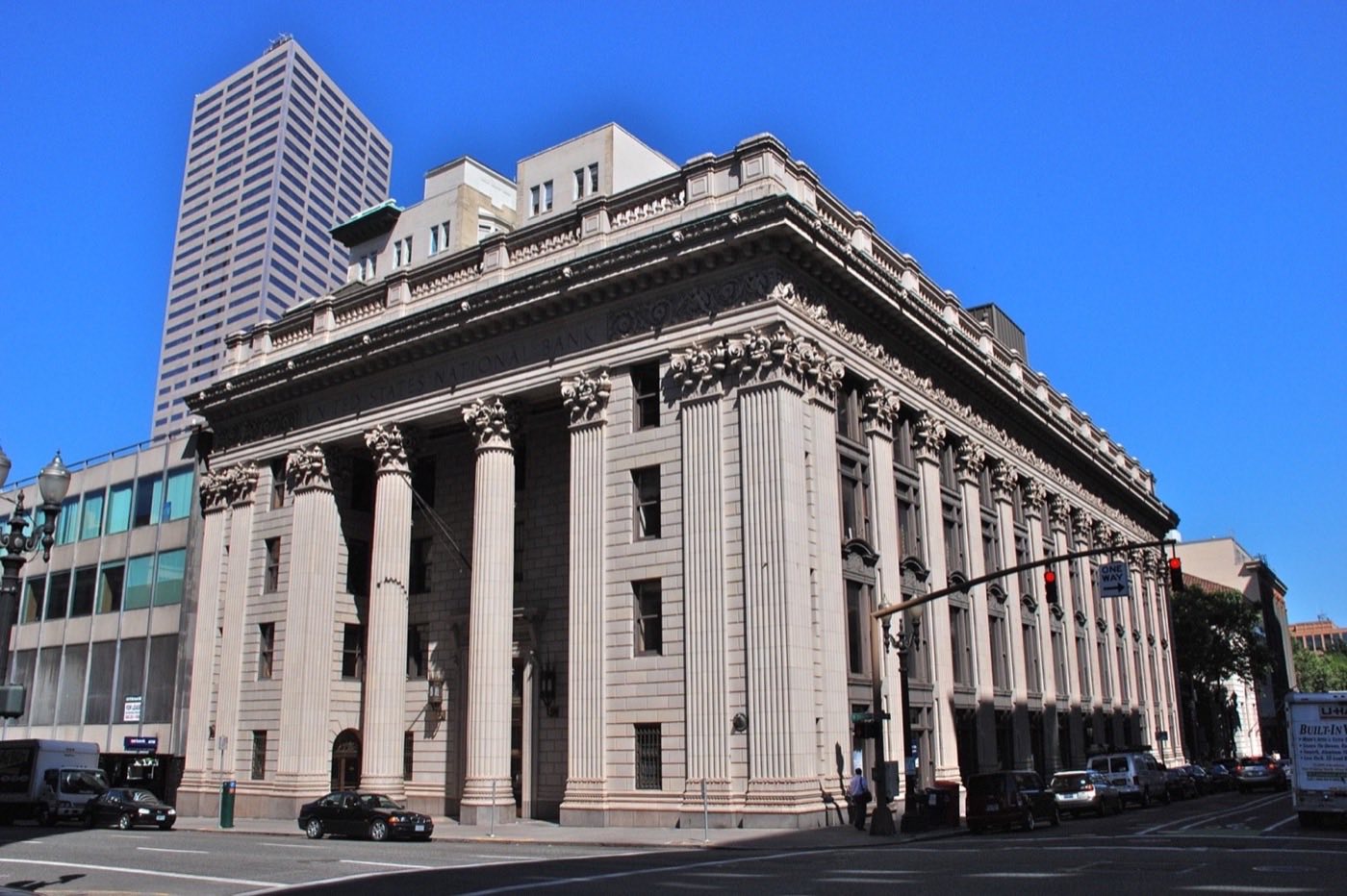 A grand neoclassical bank building with tall stone columns on a city street corner